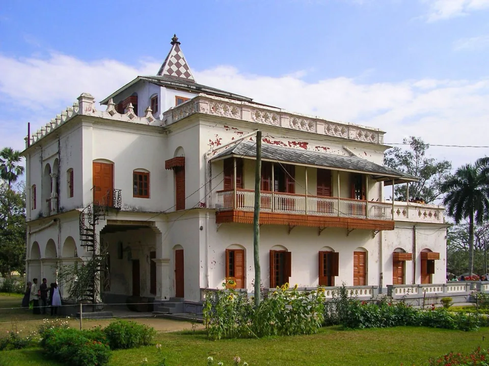 পিরামিড আকৃতির চূড়া ও কাঠের জানালাসহ সাদা শিলাইদহ কুঠিবাড়ি