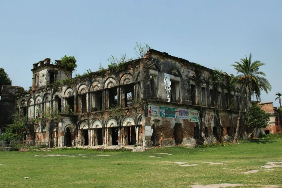 The arched, crumbling facade of Teota Zamindar Bari overgrown with plants