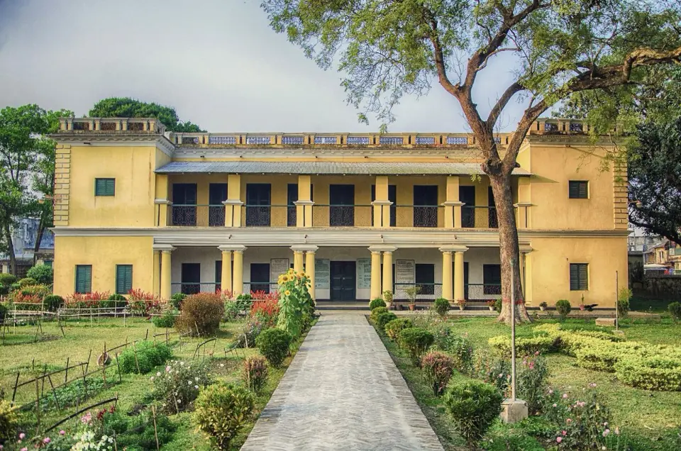 Yellow two-storey Rabindra Kachharibari with a garden path in Shahzadpur