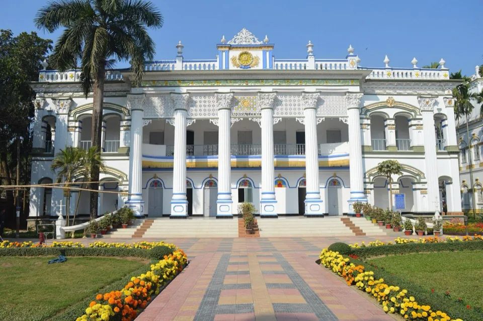 The white colonnaded front of a restored mansion at Mohera Zamindar Bari with flower beds