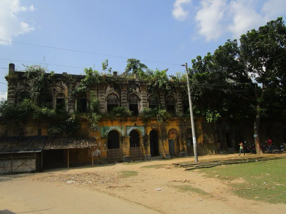 Facade of the overgrown Haripur Rajbari with arched windows